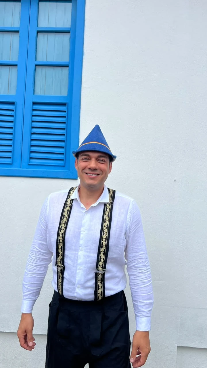 Hans Dettmann de frente junto a uma janela azul e uma parede clara.